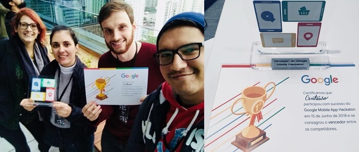 Duas mulheres e dois homens segurando um troféu e um certificado do evento Hackathon do Google