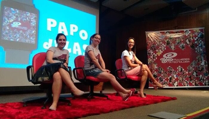Três profissionais sentadas em cadeiras no palco do evento Mulheres na Tecnologia
